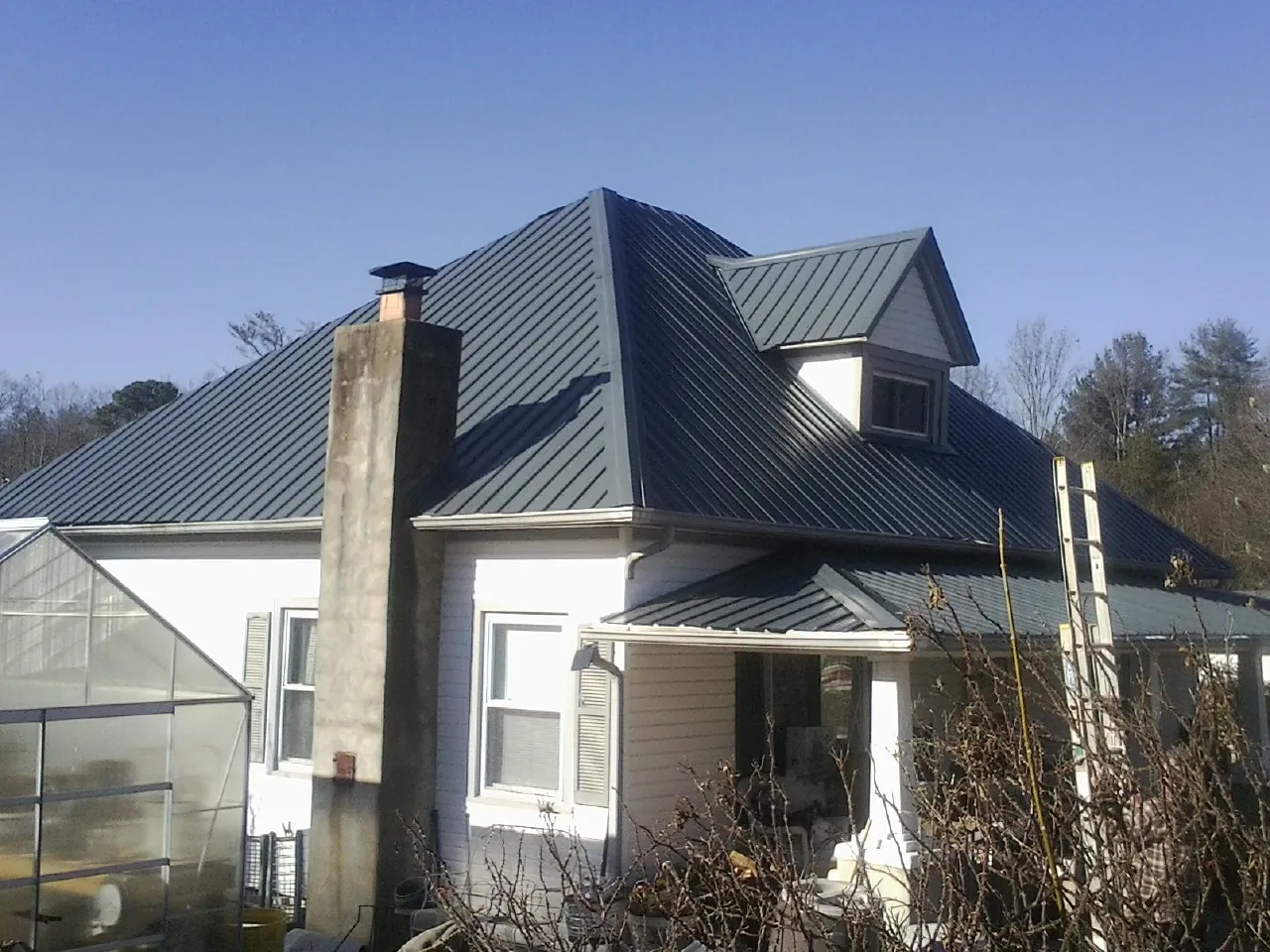 Dark blue standing seam metal roof on a white farmhouse with dormer — Slate & Tile Roof Repair by Roofing Brothers in Leiters Ford