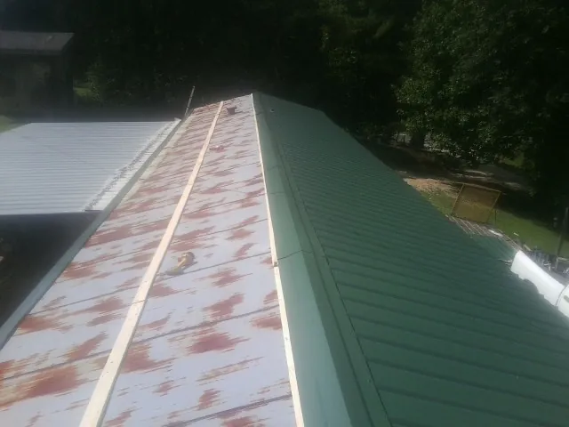 Old rusted panels beside newly installed green metal roofing — Wind Damage Roof Repair by Roofing Brothers in Leiters Ford