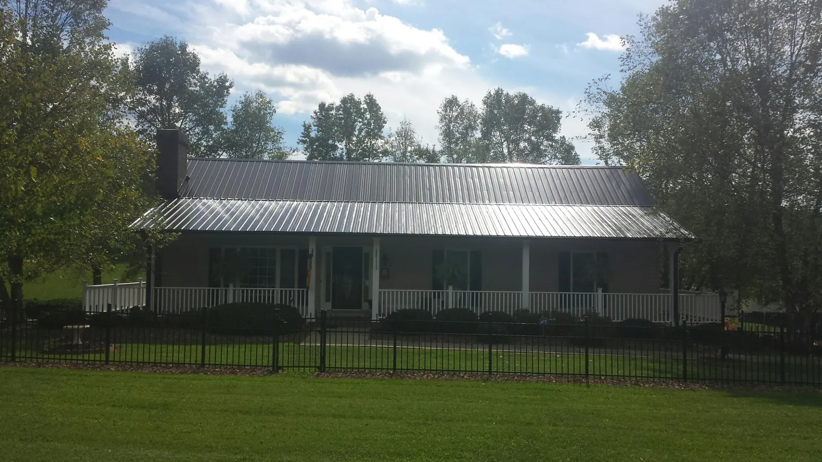 Gray metal roof on a brick ranch with a full width front porch — Gutter Guard Installation work by our crew in Leiters Ford