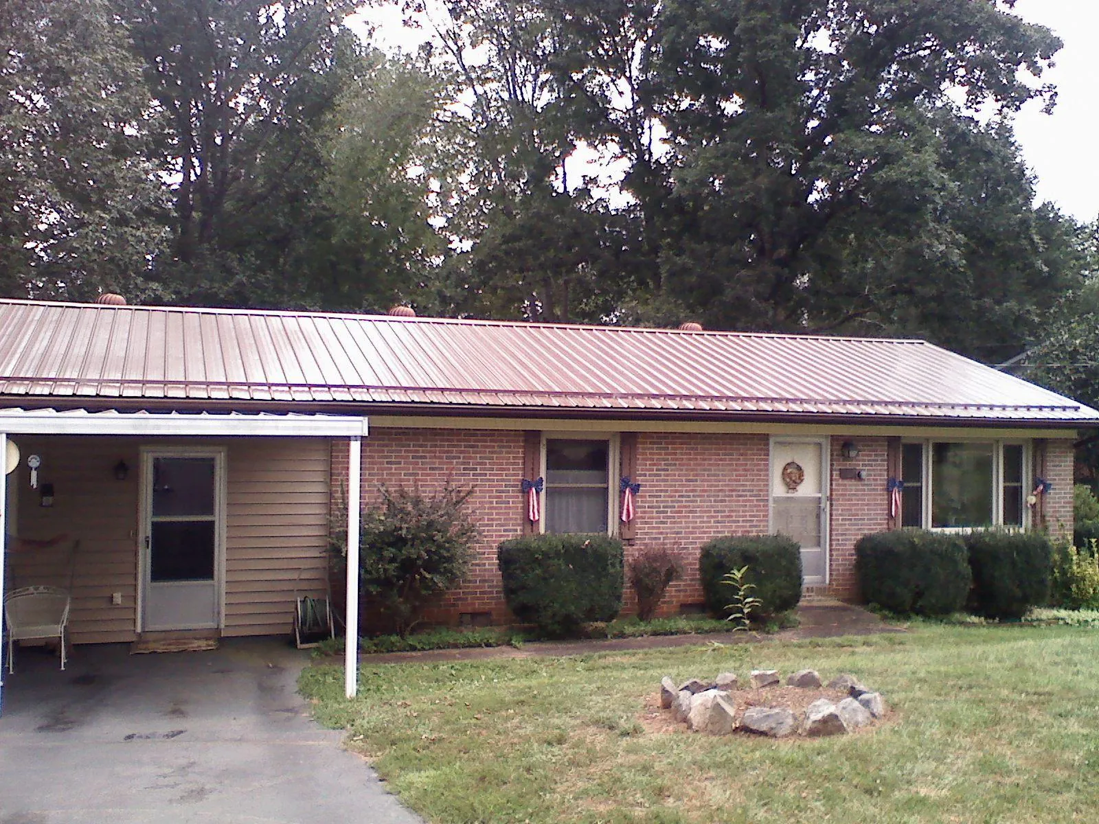 Bronze metal roof and carport on a brick ranch home — Roof Repair work by our crew in Leiters Ford