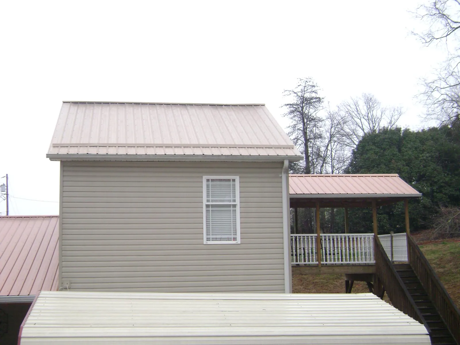 Tan metal roofs on a two story addition and attached porch, from a Roof Replacement job in Leiters Ford