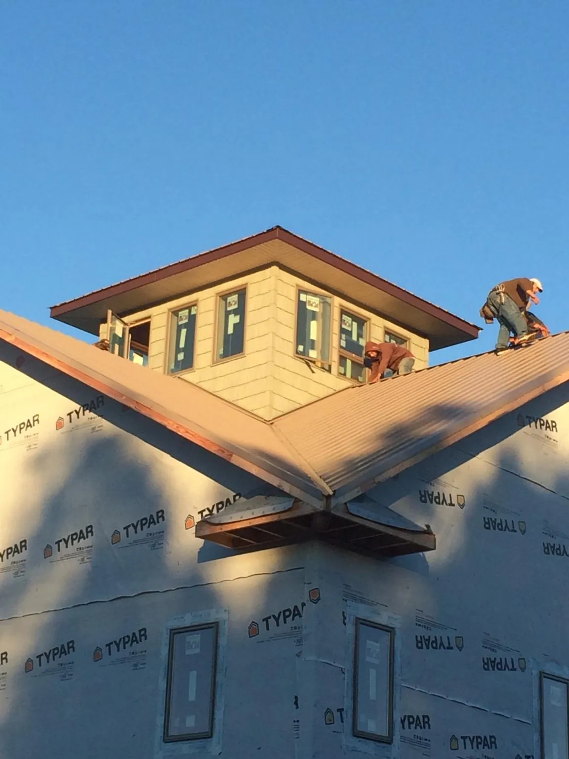 Roofers working around a rooftop cupola on a new metal roof at sunset — Roof Waterproofing in Leiters Ford by Roofing Brothers